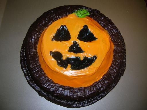Jack-O-Lantern Cake.JPG - For Halloween, make a jack-o-lantern cake. Press a 3/4-inch layer of clay around the edges of the bottom of a deep, round pan. Smooth the edges down towards the center, such there is a large center well in the clay. Along the middle of the well, form a thin layer of the clay, such that at least some clay is covering all of the bottom of the pan. Make triangles of the clay for the eyes and nose, position them in the center of the pan, and smooth the edges of the triangles into the bottom thin layer. Make the mouth in a similar fashion. Spray the pan and clay with cooking spray, and pour cake batter until it is about 3/4-inch above the highest portion of the clay. Bake until done, loosen the cake from the sides of the pan, and invert the pan.Added by: Admin.